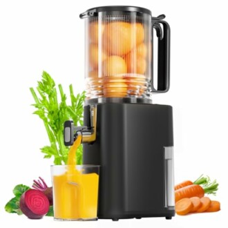 Electric juicer with oranges and fresh juice surrounded by vegetables.