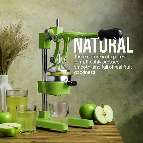 Green manual juicer with glasses of juice and apples.