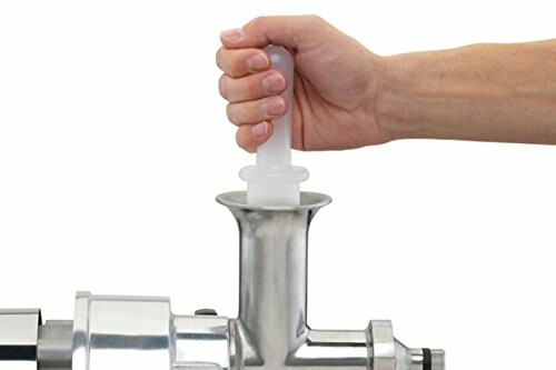 Hand pushing meat into a grinder.
