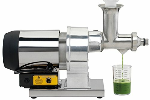 Industrial juicer extracting green juice into a measuring cup.