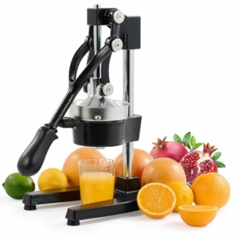 Manual citrus juicer with assorted fruits and juice glass.