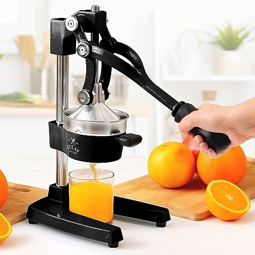 Manual citrus juicer pressing fresh orange juice into a glass.