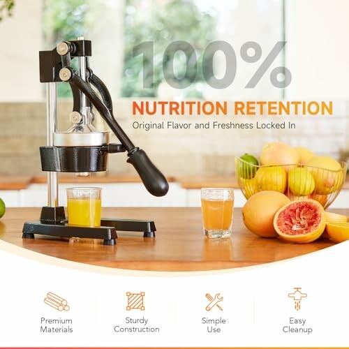 Manual juicer on a table with fresh fruit and juice glasses.
