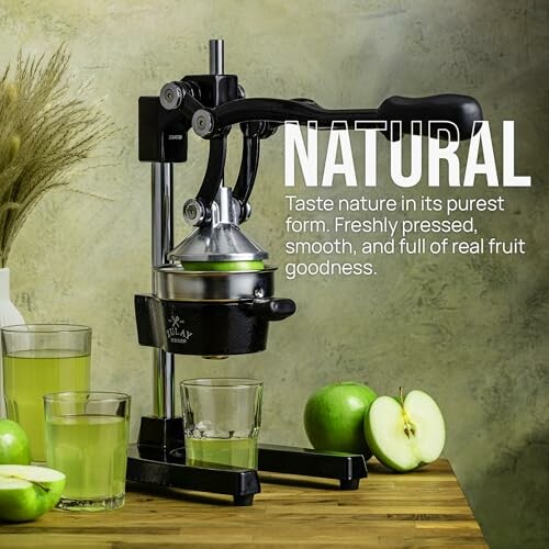 Manual juicer with glasses of green apple juice and fresh apples.