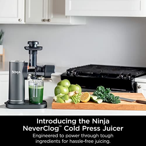 Ninja NeverClog Cold Press Juicer with green juice and ingredients on counter.