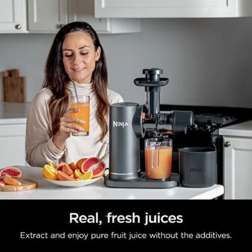 Woman enjoying fresh juice made with Ninja juicer in kitchen.